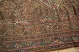 Antique Kamseh rug detail with worn pile, dusty blush geometric patterns and tattered edge.