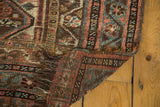 Antique Kamseh rug corner folded; multi-toned geometric patterns, tattered fringe.
