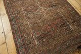 Antique Kamseh rug field with complex motifs, muted copper tones, and worn tattered fringe.