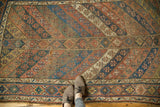 Antique Kurdish carpet's diagonal geometric pattern of navy, dusty copper, and ivory, exhibiting aged patina.