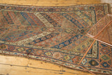 Visible wear and geometric stylized floral cross-sections of a collectible antique Kurdish rug.