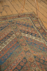 Antique Kurdish carpet detail: geometric bands in dusty copper, indigo, and ivory with knot wear.