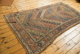 Tattered side of an Antique Kurdish Carpet, showcasing geometric borders in dusty copper and navy blue.