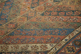 Antique Kurdish carpet's geometric motifs in dusty copper, blue, showing wear, exposed foundation.