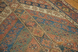 Geometric motifs in rich blues, dusty copper, and ivory with aged hand-knotted Kurdish pile.