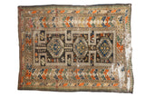 Antique Caucasian rug featuring triple medallions on a charcoal field with tangerine, green, and ivory motifs.