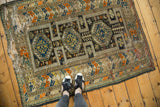 Antique Caucasian rug corner, geometric patterns in tangerine, green, charcoal, and threadbare pile.