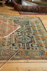 Geometric pattern detail on the antique Caucasian rug's border and charcoal field.