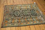 Antique Caucasian rug's right edge showing tattered fringe and geometric border patterns.