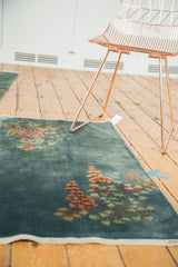 Delicate tangerine orange and celadon floral ornamentation on Art Deco rug corner.