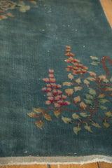 Vintage Art Deco rug: dusty blue field with rose and tangerine flowers, showing tattered fringe.