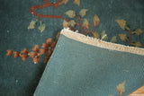 Close-up of vintage Nichols Art Deco rug: dusty blue floral pile and ribbed back.