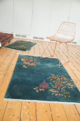 Delicate rose, tangerine, and green floral ornamentation on a blue Nichols Art Deco rug.