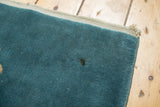 Dime-sized stain on the denim blue Art Deco rug pile, with light corner tatter.