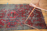 Corner of vintage Karaja rug, brick red and sky blue geometric motifs, with visible edge wear.