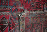 Detail of vintage Karaja rug's unsecured edge, fringing, and geometric red, blue patterns.