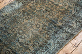 Textured distressed surface of a vintage Hamadan runner, showing faded blue herati motifs.
