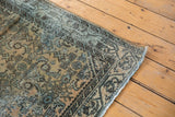 Distressed corner of vintage Persian runner with worn pile, secured fringe, and Serbend border.