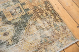 Distressed vintage Hamadan rug corner with geometric pattern and exposed foundation in sand, ivory, seafoam.