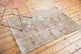 Secured side of a distressed vintage Hamadan rug, showing worn geometric patterns in ivory and brown.