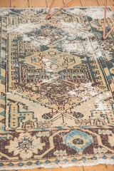 Worn texture of a vintage Hamadan rug, revealing geometric designs in dusty teal and brown.