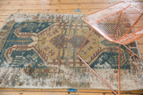 Distressed Hamadan rug's geometric patterns in faded teal and gold with worn foundation.