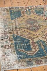 Distressed Hamadan rug edge with worn pile, exposed foundation, faded teal and sand tones.