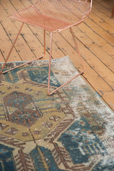 Distressed vintage Hamadan rug detail showing faded teal, gold, sand tones, and visible foundation.