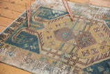 Distressed texture with geometric motifs in faded teal, saffron, and brown on a vintage Hamadan.
