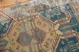 Distressed vintage Hamadan rug with geometric animal motifs in faded teal and gold.