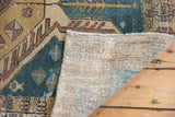 Folded corner of the vintage distressed Hamadan rug, showing worn pile and foundation.