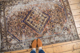 Distressed Hamadan rug with worn texture, serrated medallion, and herati motifs.