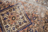 Distressed Hamadan rug fragment with serrated diamond medallion, herati motif, and exposed foundation.