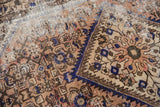 Distressed vintage Hamadan rug detail with serrated cobalt blue edge and herati motifs.