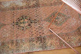 Detail of distressed vintage Hamadan rug featuring faded rose, blush, and exposed foundation.