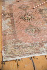 Distressed Hamadan rug corner with visible wear, fringe, and faded rose, beige, mint green.