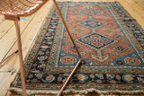 Antique Heriz runner displaying terra cotta field, diamond medallions, and lively blue geometric patterns.