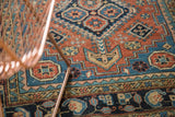 Antique Heriz rug section: terra cotta field with geometric motifs, sky blue and navy border.