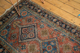Close-up of antique Heriz runner's terra cotta field, geometric medallions, and navy blue border.