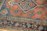 Hand-knotted Heriz rug detail: terra cotta field with geometric motifs and intricate navy borders.