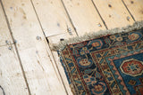 Hand-knotted fringe and corner of the antique Heriz rug, with terracotta, navy, and sky blue motifs.