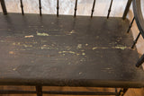 Close-up of antique Deacon's Bench seat, highlighting distressed dark paint with green chips and cracks.