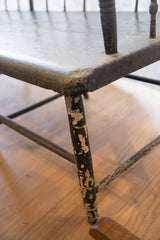 Leg detail of the antique Deacon's Bench with chipping black paint and patina.