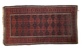 Antique Belouch rug showcasing bold geometric gul motifs in madder red, navy, and charcoal.