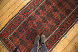 Standing perspective of a hand-knotted Antique Belouch rug with bold madder red and navy geometric gul motifs.