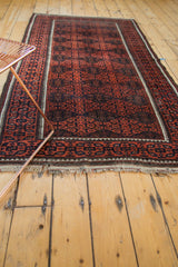 Geometric gul motif and soft fringe of the antique Belouch rug, showcasing madder red and ivory.