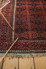 Textured fringe and bold madder root red geometric gul motifs of an antique Belouch rug.