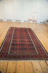 Fringe and corner of an early 20th century Belouch rug, showcasing madder red and navy geometric gul motifs.