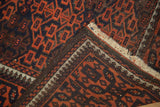Folded Antique Belouch rug, highlighting secure sidecord selvage, fringe, and madder root red gul motif.