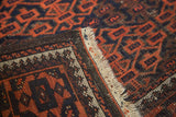 Soft wool, madder red and navy geometric gul motifs on antique Belouch rug corner.